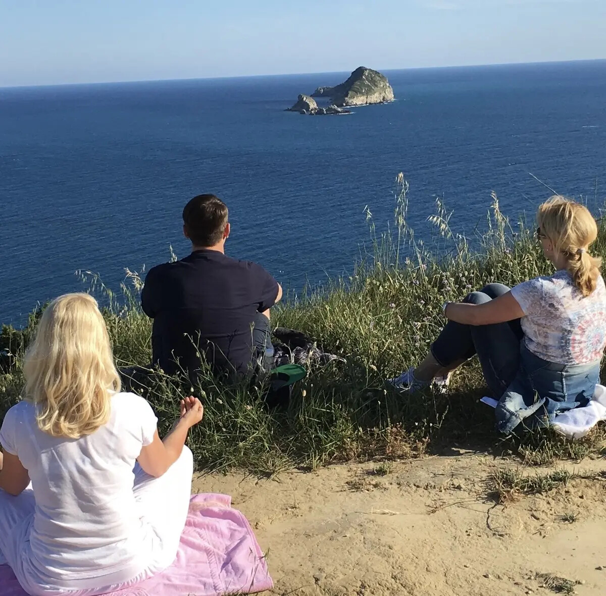 Drei Teilnehmende meditieren auf Korfu mit Blick auf das Ionische Meer